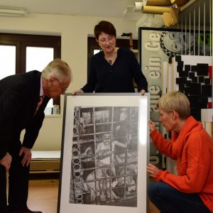 Bettina Müller und Rainer Krätschmer lassen sich von der Jossgrunder Künstlerin INK Sonntag-Ramirez Ponce (Mitte) die Arbeiten aus ihrem Bilderzyklus Mit dem Rücken zur Wand erläutern.